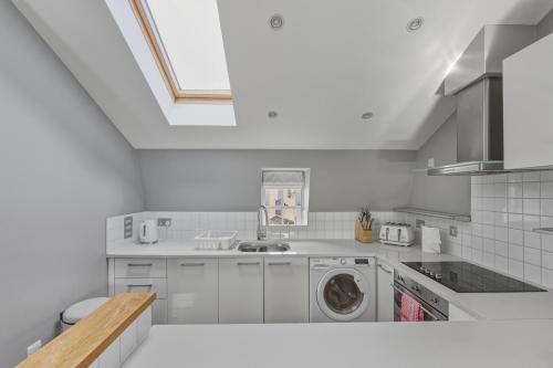 a white kitchen with a washing machine in it at Stylish 2BR Retreat Steps from Kings Cross in London