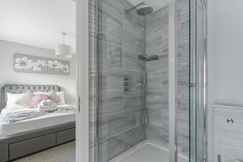 a bathroom with a shower and a bed with a glass door at Stylish 2BR Retreat Steps from Kings Cross in London