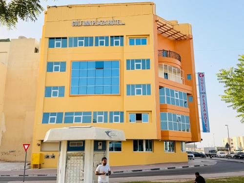 Ein Mann steht vor einem gelben Gebäude. in der Unterkunft Gulf inn Plaza Hotel LLC in Dubai