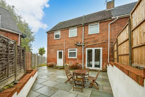 een patio met een tafel en stoelen voor een bakstenen gebouw bij Stanmore House - Winchester 