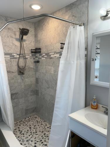 Una ducha con una cortina de ducha blanca y un lavabo. en Comfortable, Spacious 3-BR, 2-BA-1 level home- DEEP dock on canal, Islamorada, en Islamorada