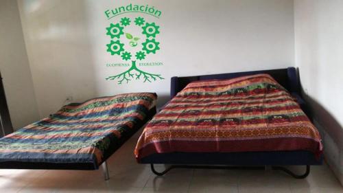 two beds in a room with a sign on the wall at Finca Campestre Foundation Ecopiensa Evolution in Andalucía