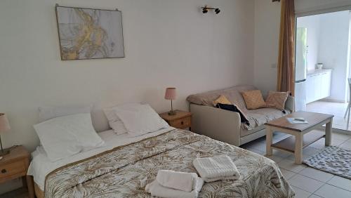 a bedroom with a bed and a table and a couch at Rêve Créole, accès plage et piscine in Saint-François