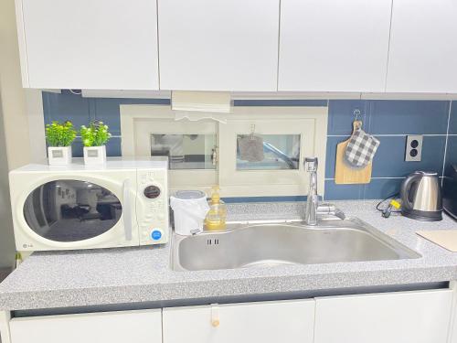 a kitchen counter with a sink and a microwave at 달빛그리기Moonlight in Daegu