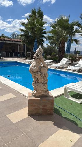 a statue sitting next to a swimming pool at Villa Liliana Piroska in San Giuseppe Jato