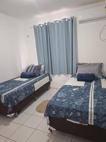 a bedroom with two beds and a window with curtains at my sweet place 18 in São Luís