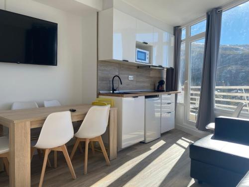 a kitchen with a wooden table and white chairs at Apartamento Plaza Pradollano 1 in Sierra Nevada