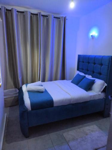een slaapkamer met een groot blauw bed met gordijnen bij Poshairbnb in Nairobi