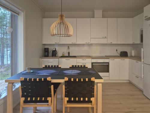 una cucina con mobili bianchi e un tavolo con sedie di Villa Arvoranta a Nellimö