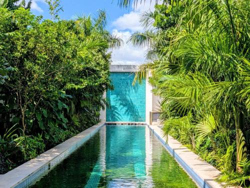 une piscine dans un jardin avec des arbres et un bâtiment dans l'établissement El Pueblo Mérida, à Mérida