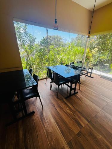 una sala da pranzo con tavolo e sedie e una grande finestra di Casa Nube Resort Munnar a Munnar