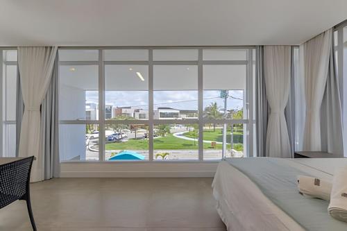 Schlafzimmer mit einem großen Fenster mit Poolblick in der Unterkunft Casa de Luxo em Condomínio na Barra de São Miguel in Barra de São Miguel