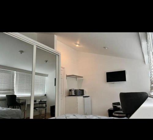 a bedroom with a mirror and a table and a kitchen at An En-suite with a mini kitchen and a work space in London