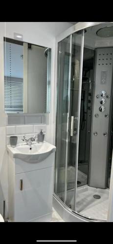 a bathroom with a sink and a shower with a mirror at An En-suite with a mini kitchen and a work space in London