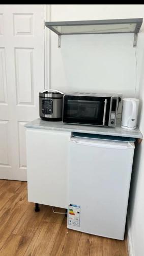 a microwave sitting on top of a white refrigerator at An En-suite with a mini kitchen and a work space in London