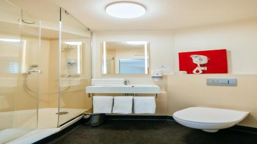 a bathroom with a shower and a toilet and a sink at B&B HOTEL Katowice Centrum in Katowice