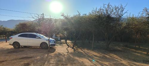 a white car parked on a dirt road next to trees at Antar Mouna in Cortaderas