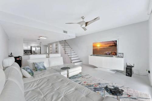 a white living room with a couch and a staircase at Waterfront Two-Bedroom Townhome with Canal View in Highland Beach
