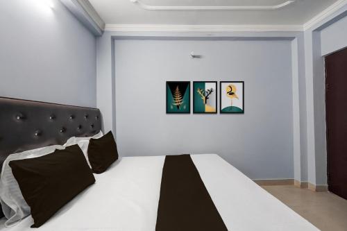 a white bedroom with a bed with black pillows at Hotel O STAR GALAXY in Bhauli