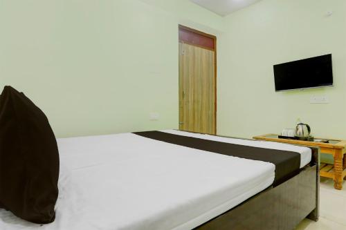 a bedroom with a white bed with a television at Hotel O Ansh Raj Hotel in Patna City