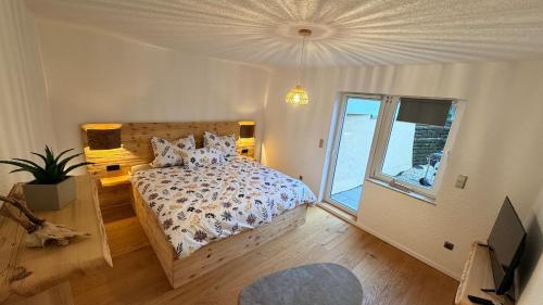 een slaapkamer met een bed en een groot raam bij TheWoodenStack in Waldachtal