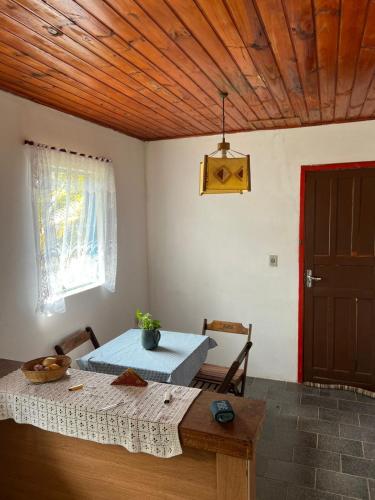 a room with a table and a window and a wooden ceiling at Cantinho Philot in Nova Friburgo