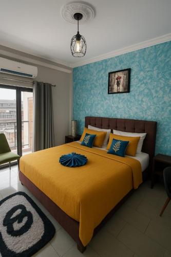 a bedroom with a large yellow bed with blue walls at Residence JTC in Douala