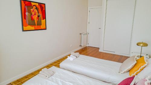 two beds in a room with a painting on the wall at Sea & City Escape in Matosinhos