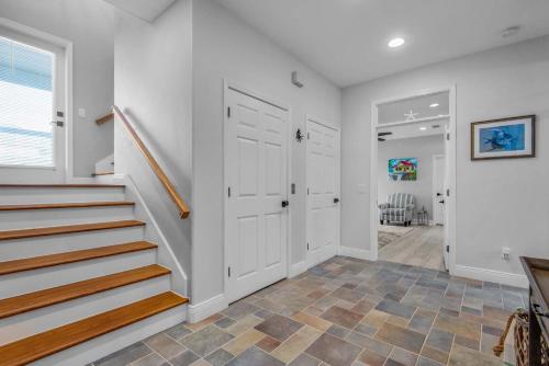 a hallway with white walls and stairs and a door at Bella Vista by Gulf Coast Getaways in Pensacola Beach
