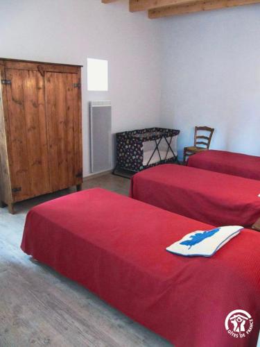 a room with three beds with red sheets at Le Mas de la Tourelle in Roussennac