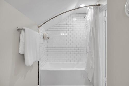 a white bathroom with a shower with white towels at MidTown Cozy Cottage in Indianapolis