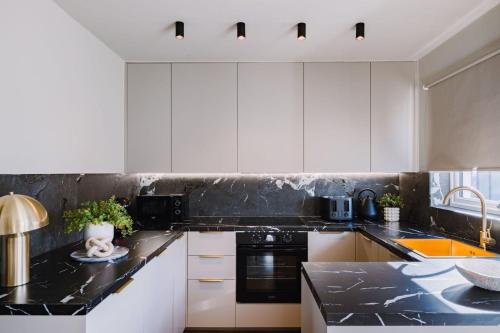 een keuken met witte kasten en een zwart aanrechtblad bij JW Executive ApartHouse in Glasgow