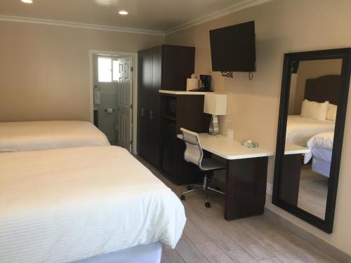 a hotel room with two beds and a desk and a mirror at El Royale Hotel - Near Universal Studios Hollywood in Los Angeles