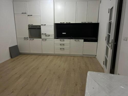 a kitchen with white cabinets and a flat screen tv at Banesa Mitrovice in Mitrovicë