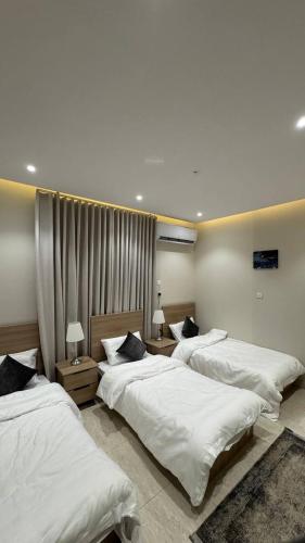 a bedroom with three beds with white sheets at Rest home in Tabuk