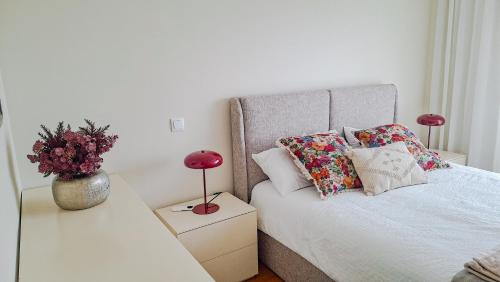 a bedroom with a bed with pillows and flowers on it at Sea & City Escape in Matosinhos