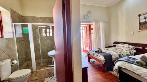 une chambre avec un lit et une salle de bain avec douche dans l'établissement Kroon Lodge, à Kamieskroon