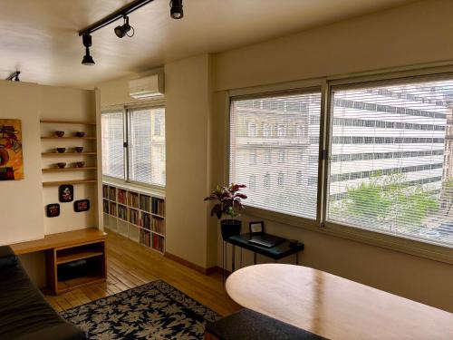 Una sala de estar con una mesa y dos ventanas. en Estilo y Comodidad en Av Corrientes, departamento con cochera para autos, en Buenos Aires