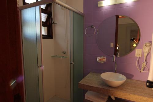 a bathroom with a sink and a mirror and a shower at Chalés Saint Germain in Florianópolis