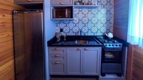 a small kitchen with a sink and a stove at Chalé Romântico com jacuzzi e café da manhã em Rancho Queimado in Rancho Queimado