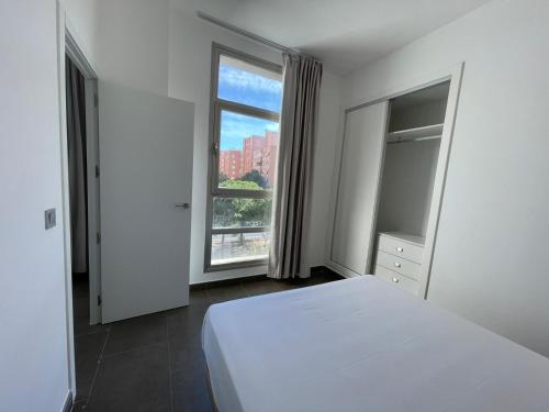 a bedroom with a white bed and a large window at Palm Suites Gran Vía in Alicante