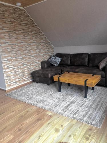 ein Wohnzimmer mit schwarzem Sofa und Couchtisch in der Unterkunft Holiday Nest 2 in Sønderborg