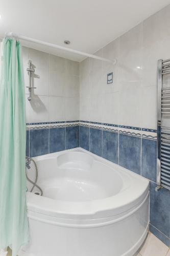 a white bath tub in a bathroom with blue tiles at Wood Green Central Cozy Rooms in London