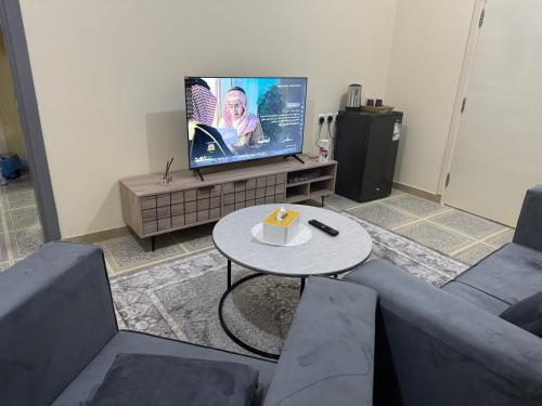 Una sala de estar con un sofá, una mesa y un televisor. en ANA Apartment, en Hail