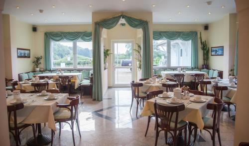 un restaurante con mesas, sillas y ventanas en Hotel Atlantis en Ramstein-Miesenbach