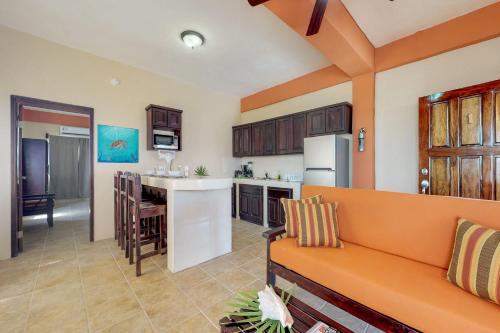 eine Küche und ein Wohnzimmer mit einem orangefarbenen Sofa in der Unterkunft Honey Camp #1 at Laguna Suite -Gold Standard Certified in San Pedro