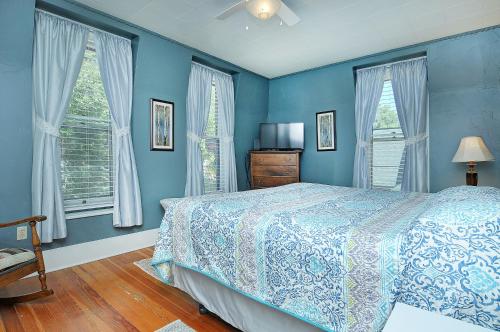 a blue bedroom with a bed and two windows at The Caddis Cottage in Salida