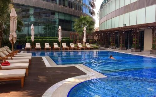 a pool in a hotel with chairs and a person swimming at Premium Vacation Home in Old Dubai Nr Metro Mall in Dubai