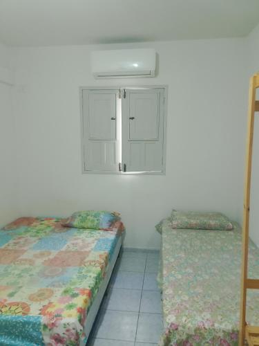 ein Schlafzimmer mit zwei Einzelbetten und einem Fenster in der Unterkunft Hostel da Josi - Porto de Galinhas in Porto De Galinhas