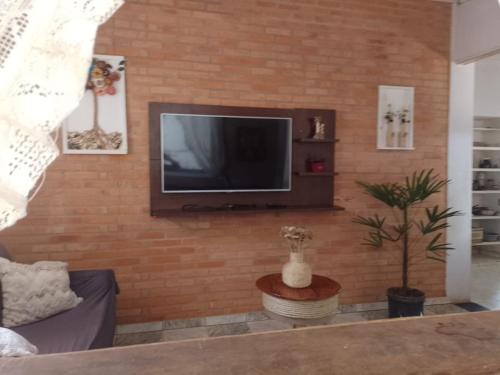a living room with a television on a brick wall at Sitio Recanto das águas in São João del Rei